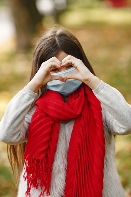 Young girl in red scarf making a heart gesture